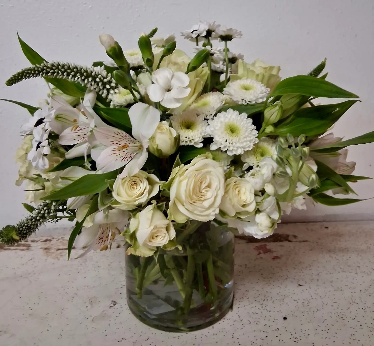 white freesias, white roses, Lisianthus, White Veronica, White Chrysanthemums in a vase