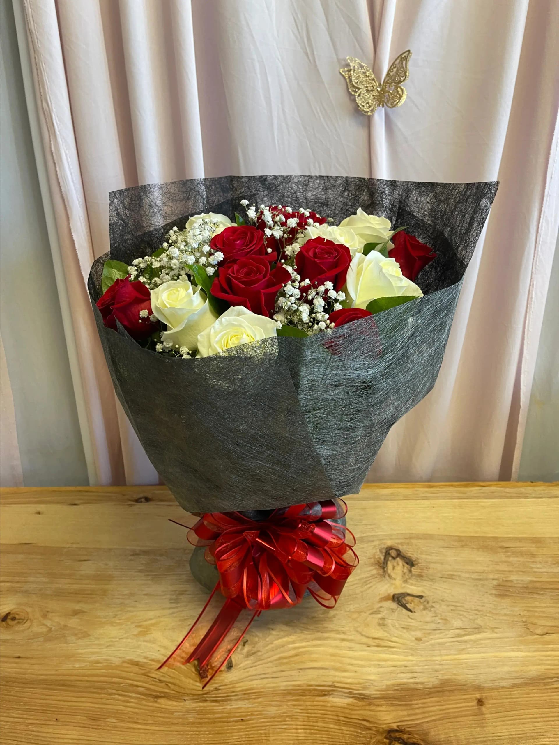 1 dozen roses of mixed red and white color wrapped in black lace bouquet wrapping with red bow
