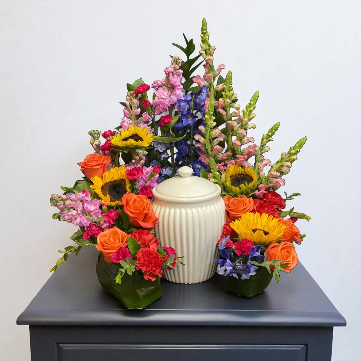 Colorful urn surround with sunflowers, red, blue, and yellow flowers
