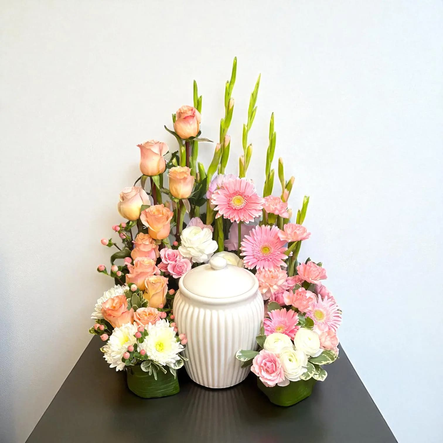 Peach and pink cremation urn surround with fresh flowers