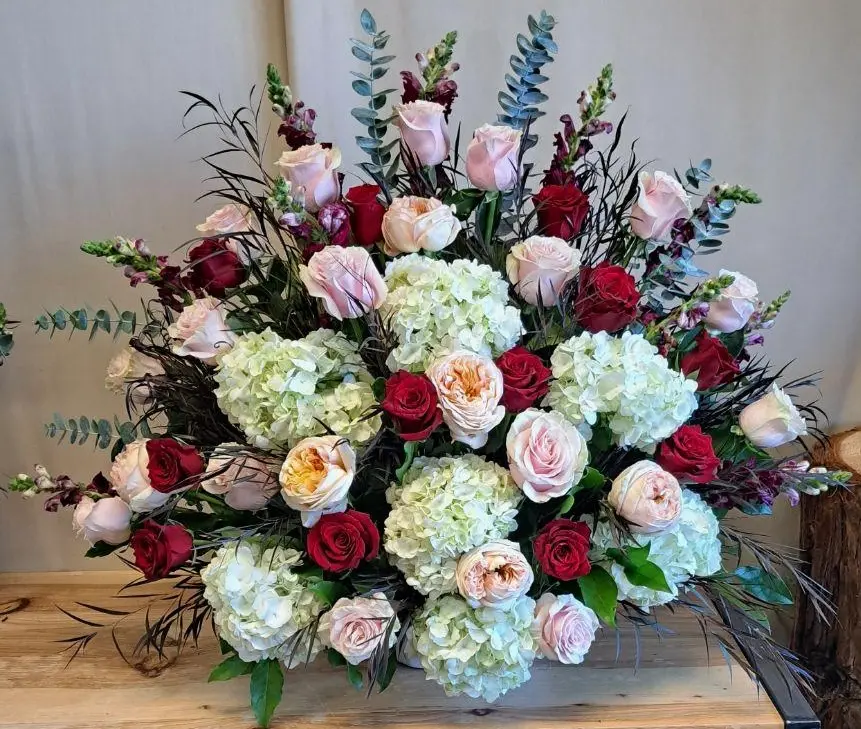 red roses, pink roses, white hydrangeas and greenery in a basket